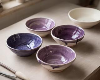 Piccole ciotole artigianali smaltate in tonalità viola su un banco