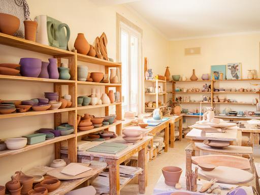 Interno luminoso dell'atelier di ceramica a Partinico con scaffali di manufatti