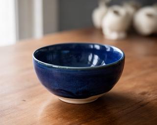 Ciotola in ceramica blu cobalto appoggiata su un tavolo in legno